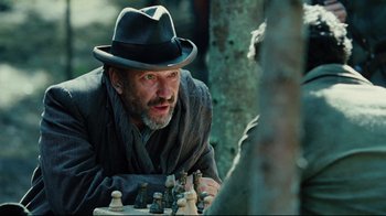 Movie still from “Defiance” (2008), directed by Edward Zwick – A man wearing a hat playing a game of chess; Close Up shot, Over the shoulder angle