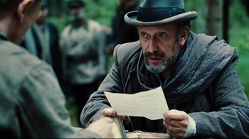 Movie still from “Defiance” (2008), directed by Edward Zwick – A man in a hat is looking at a piece of paper; Close Up shot, Over the shoulder angle