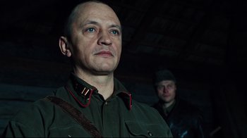 Movie still from “Defiance” (2008), directed by Edward Zwick – A man in a military uniform looking at the camera; Close Up shot, Low angle