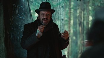 Movie still from “Defiance” (2008), directed by Edward Zwick – A man wearing a black hat and a black coat; Medium shot, Low angle