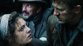 Movie still from “Defiance” (2008), directed by Edward Zwick – Two men and a woman are sitting in a group; Close Up shot, Over the shoulder angle