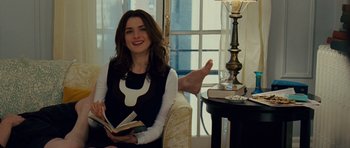 Movie still from “Definitely, Maybe” (2008), directed by Adam Brooks – A woman sitting in a chair holding an open book; Medium shot, Over the shoulder angle