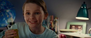 Movie still from “Definitely, Maybe” (2008), directed by Adam Brooks – A young girl smiling for the camera in front of a bookshelf; Close Up shot, High angle