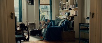 Movie still from “Definitely, Maybe” (2008), directed by Adam Brooks – A person sitting on a couch in a living room; Wide shot, High angle