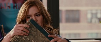 Movie still from “Definitely, Maybe” (2008), directed by Adam Brooks – A woman is holding a book in front of her face; Close Up shot, Over the shoulder angle