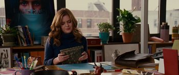 Movie still from “Definitely, Maybe” (2008), directed by Adam Brooks – A woman sitting at a table holding a book in her hands; Medium shot, Over the shoulder angle
