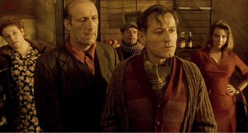 Movie still from “Delicatessen” (1991), directed by Marc Caro – A group of men standing next to each other in a room; Medium shot, Low angle