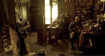 Movie still from “Delicatessen” (1991), directed by Marc Caro – A group of people sitting at a table in a room; Wide shot, High angle