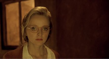 Movie still from “Delicatessen” (1991), directed by Marc Caro – A woman wearing glasses looking at the camera; Close Up shot, Over the shoulder angle
