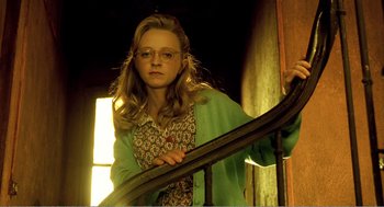 Movie still from “Delicatessen” (1991), directed by Marc Caro – A young woman wearing glasses standing next to a railing; Medium shot, Low angle