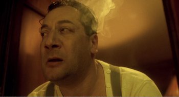 Movie still from “Delicatessen” (1991), directed by Marc Caro – A person smoking a cigarette; Close Up shot, Low angle