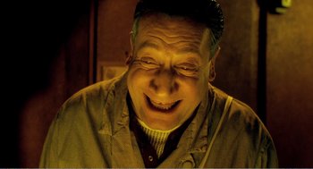 Movie still from “Delicatessen” (1991), directed by Marc Caro – An older man smiling with his mouth open; Close Up shot, Overhead angle