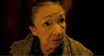 Movie still from “Delicatessen” (1991), directed by Marc Caro – An older woman looking at the camera with an angry look on her face; Close Up shot, High angle