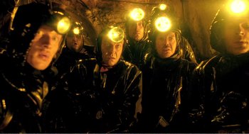 Movie still from “Delicatessen” (1991), directed by Marc Caro – A group of men in black jackets and headlamps; Medium shot, Low angle