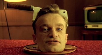 Movie still from “Delicatessen” (1991), directed by Marc Caro – A man with a knife on his head is sitting on a plate; Close Up shot, Overhead angle