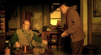 Movie still from “Delicatessen” (1991), directed by Marc Caro – Two men are standing in a room and one of them is wearing a sweater; Medium shot, Low angle