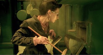 Movie still from “Delicatessen” (1991), directed by Marc Caro – A woman in a black dress holding a pair of gloves and a brush; Medium shot, Low angle