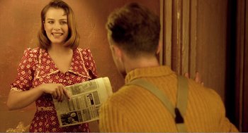 Movie still from “Delicatessen” (1991), directed by Marc Caro – A woman is holding a newspaper while a man looks in the mirror; Medium shot, Over the shoulder angle