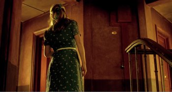Movie still from “Delicatessen” (1991), directed by Marc Caro – A woman in a green dress standing in front of a wall; Medium shot, Low angle