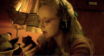 Movie still from “Delicatessen” (1991), directed by Marc Caro – A woman wearing headphones looking at a cell phone; Close Up shot, High angle