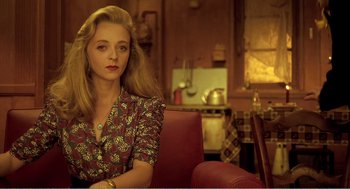 Movie still from “Delicatessen” (1991), directed by Marc Caro – A woman sitting on a red chair in a room; Medium shot, Over the shoulder angle