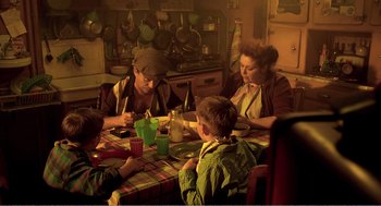 Movie still from “Delicatessen” (1991), directed by Marc Caro – A group of people sitting at a table eating food; Wide shot, High angle