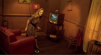 Movie still from “Delicatessen” (1991), directed by Marc Caro – A woman standing in front of an old fashioned tv set; Wide shot, High angle
