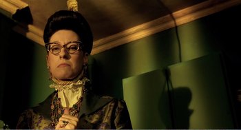 Movie still from “Delicatessen” (1991), directed by Marc Caro – A woman in a wig and glasses is posing for a picture; Close Up shot, Low angle