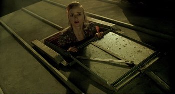 Movie still from “Delicatessen” (1991), directed by Marc Caro – A woman laying on top of a metal structure; Medium shot, Overhead angle