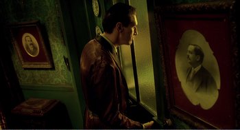 Movie still from “Delicatessen” (1991), directed by Marc Caro – A man standing in front of a mirror in a dark room; Medium shot, Over the shoulder angle