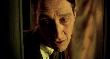 Movie still from “Delicatessen” (1991), directed by Marc Caro – A person wearing a suit and tie; Close Up shot, Low angle