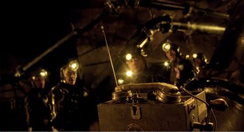 Movie still from “Delicatessen” (1991), directed by Marc Caro – A group of people in a dark room with lights on; Medium shot, Low angle