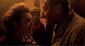 Movie still from “Delicatessen” (1991), directed by Marc Caro – A group of men and women standing next to each other; Medium shot, Over the shoulder angle