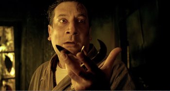 Movie still from “Delicatessen” (1991), directed by Marc Caro – A man holding a pair of pliers up to his face; Close Up shot, Low angle