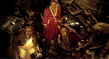 Movie still from “Delicatessen” (1991), directed by Marc Caro – A group of people sitting on the ground in a pile of trash; Wide shot, Overhead angle
