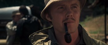 Movie still from “Deliverance” (1972), directed by John Boorman – A person wearing a hat and holding a pipe; Close Up shot, Low angle