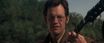 Movie still from “Deliverance” (1972), directed by John Boorman – A person wearing glasses and holding a cigarette; Close Up shot, Over the shoulder angle