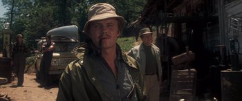 Movie still from “Deliverance” (1972), directed by John Boorman – A man with a hat smoking a pipe while standing next to another man; Close Up shot, Low angle