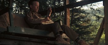 Movie still from “Deliverance” (1972), directed by John Boorman – A man sitting on top of a bench holding a guitar; Medium shot, Low angle