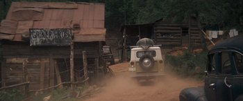 Movie still from “Deliverance” (1972), directed by John Boorman – A truck driving down a dirt road near a wooden building; Wide shot, Low angle
