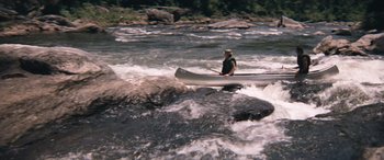 Movie still from “Deliverance” (1972), directed by John Boorman – A man is paddling a canoe in the water; Wide shot, High angle