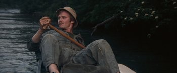 Movie still from “Deliverance” (1972), directed by John Boorman – A man sitting on a raft in the water; Medium shot, Low angle