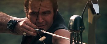 Movie still from “Deliverance” (1972), directed by John Boorman – A person holding a bow and arrow; Close Up shot, Low angle