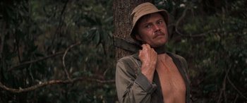 Movie still from “Deliverance” (1972), directed by John Boorman – A man in a hat is standing next to a tree; Close Up shot, Low angle