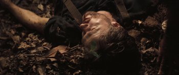 Movie still from “Deliverance” (1972), directed by John Boorman – A man laying on top of a pile of dead leaves; Close Up shot, Overhead angle