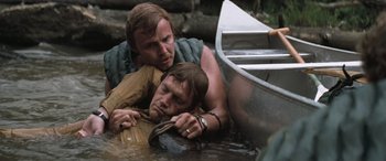 Movie still from “Deliverance” (1972), directed by John Boorman – Two men are in the water and one is holding a boat; Close Up shot, High angle