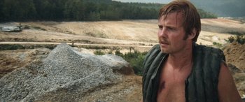 Movie still from “Deliverance” (1972), directed by John Boorman – A man with no shirt standing on a dirt road; Close Up shot, Over the shoulder angle