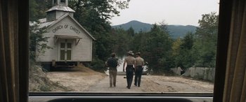 Movie still from “Deliverance” (1972), directed by John Boorman – A couple of men walking down a dirt road near a house; Extreme Wide shot, High angle