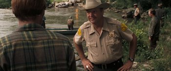 Movie still from “Deliverance” (1972), directed by John Boorman – A man in a hat is standing on a boat; Medium shot, Over the shoulder angle
