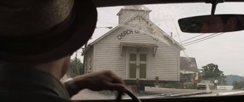 Movie still from “Deliverance” (1972), directed by John Boorman – A person driving a car in front of an old church; Wide shot, Low angle